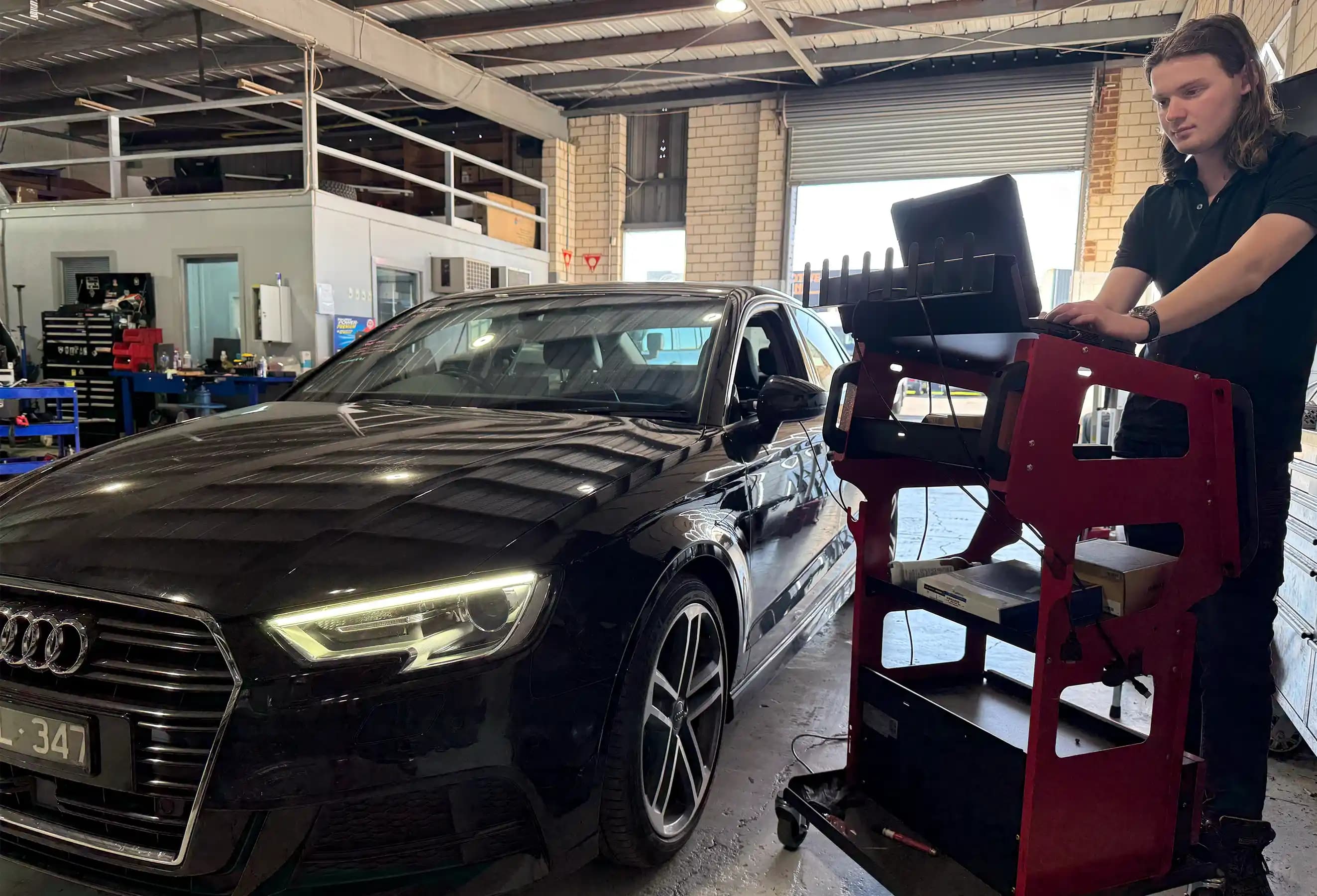 Technician using advanced diagnostic equipment for ADAS calibration on an Audi vehicle in a professional Melbourne garage